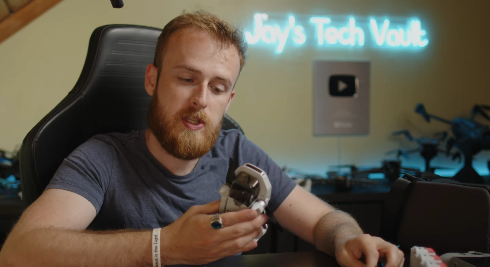 A creator at a desk holding camera equipment while filming a video.